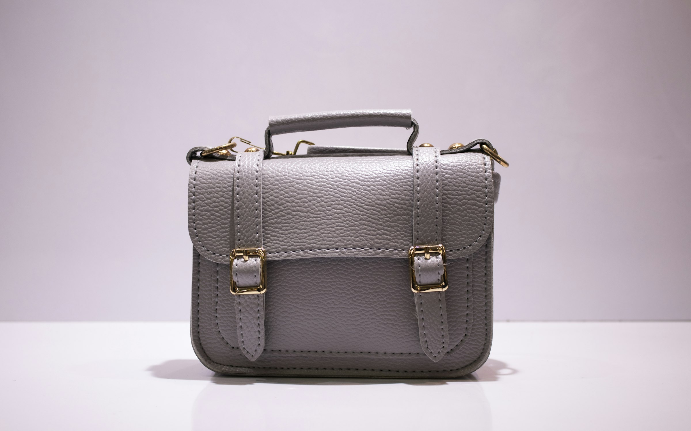 A grey leather satchel with gold buckles